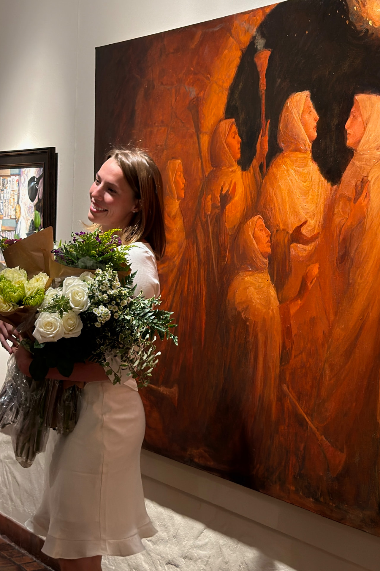 Emma beside The Torchbearers painting, holding flowers